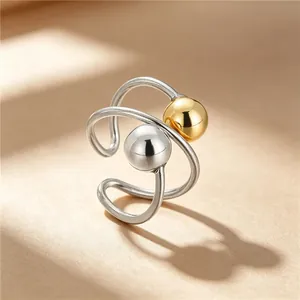 Close-up of a stainless steel ring featuring silver and gold metallic beads and geometric design.