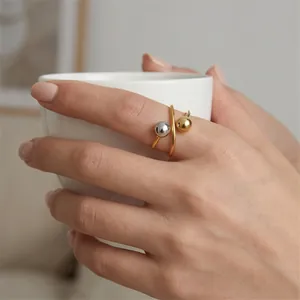 Detailed view of a stainless steel geometric open ring with dual-tone metal beads.