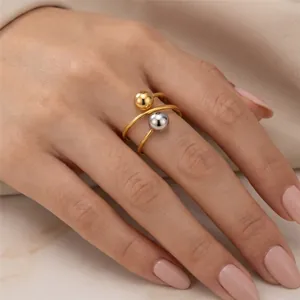 Close-up detail of a minimalist stainless steel ring with gold and silver balls on a finger