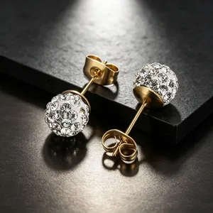Gros plan de boucles d'oreilles en acier doré avec des boules Shamballa en cristal brillant.