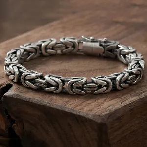 Gros plan détaillé d'un bracelet de chaîne byzantine en acier inoxydable sur bois
