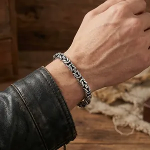 Gros plan d'un bracelet byzantin en acier inoxydable vintage sur un poignet masculin