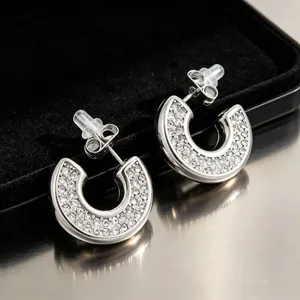 Close-up detail of stainless steel C-shaped earrings with sparkling cubic zirconia crystals