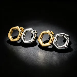 Detailed macro view of hexagonal hollow stud earrings in polished gold and silver finishes