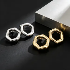 Detailed view of minimalist 18K gold-plated and silver hexagonal stud earrings on black surface
