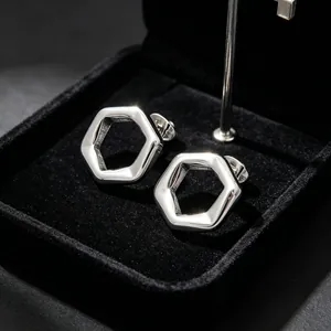 Macro view of silver-toned hexagonal hollow titanium steel earrings in a black gift box.