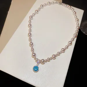 Collana di perle elegante con un brillante ciondolo a cerchio in gemma blu di lusso