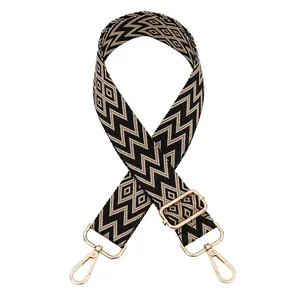 Detail view of woven geometric patterned handbag strap with gold-tone metal clips