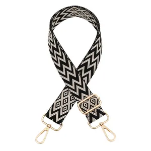Detail view of jacquard bag strap with black and white geometric patterns and gold clips