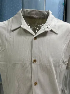 Macro detail of men's casual beige corduroy short sleeve shirt with brown buttons.