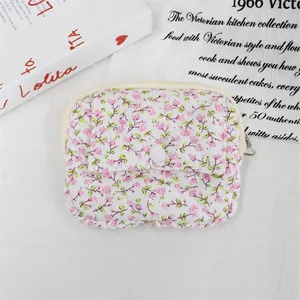Detail view of a quilted floral mini pouch with a secure flap button and zip closure.