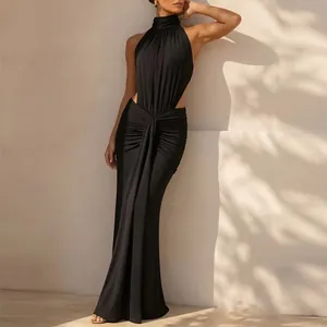 Vue de profil d'une robe longue noire à licou avec découpes à la taille au soleil.