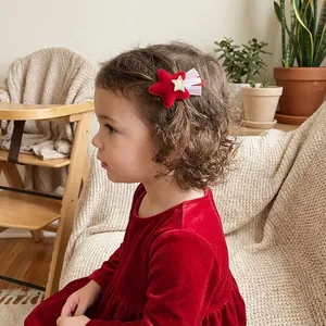 Détail d'une fille portant une pince à cheveux étoile en velours rouge avec pompons