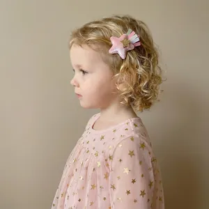 Gros plan d'une fillette portant une barrette en velours rose en forme d'étoile à glands.