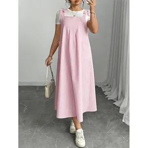 Close-up of a pink striped pinafore dress featuring cute bow shoulder strap details for summer