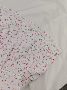 Close-up view of the delicate pink floral pattern on a white V-neck mini summer dress