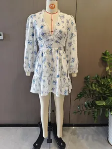 Robe courte blanche élégante à fleurs bleues, col en V et dentelle sur mannequin de présentation.