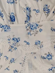 Close-up detail of exquisite blue floral print and elegant white lace trim on a summer dress