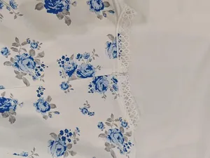 Detail showing white lace trim and blue floral print on an elegant summer mini dress.