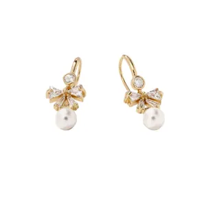 Élégantes boucles d'oreilles nœud dorées avec zircons et perles blanches