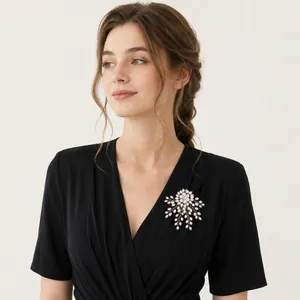 Elegant pearl firework brooch pinned on a black V-neck dress detail view