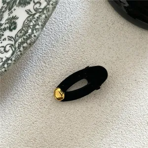 Elegant black velvet oval hair clip featuring a minimalist gold irregular bean accent for women