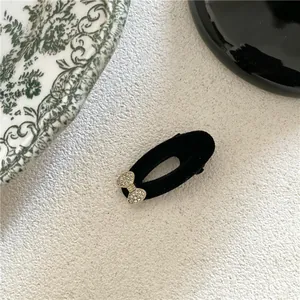 Elegant black velvet oval hair clip featuring a delicate sparkling rhinestone bow