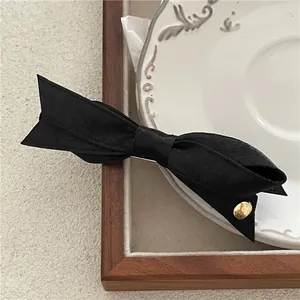 Élégante barrette à cheveux avec nœud noir mat et détail décoratif en métal doré