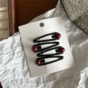 Set of 4 elegant black teardrop hair clips decorated with red beads on a white display card