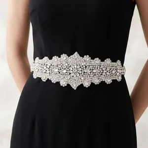 Close-up of elegant crystal bridal belt with intricate floral pattern on black evening dress
