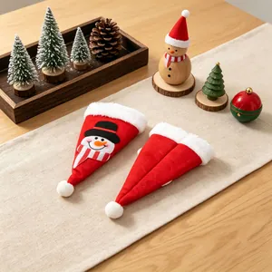 Mini porte-couverts en forme de bonnet de Noël sur un chemin de table festif.