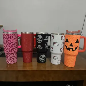 Close-up of rhinestone-encrusted insulated tumblers with Halloween and cartoon patterns.