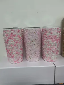 Close-up detail of three stainless steel tumblers covered in pink and white pearls