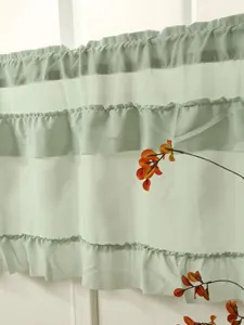 Detail view of light green tiered ruffled curtains with elegant cake skirt design