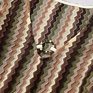 Close-up of V-neck knit dress with metallic ring detail and colorful zigzag pattern