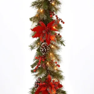 Lush artificial Christmas garland with warm LED lights red flowers and berries on white background