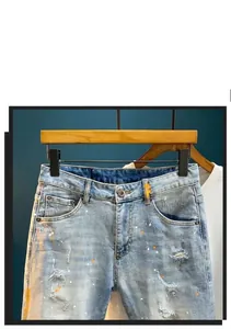 Detailed shot of light blue distressed denim shorts featuring paint splatters and ripped edges.