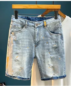 Close-up of distressed light blue denim shorts with trendy orange paint splatter details.