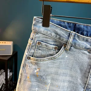 Men's high street fashion light wash denim shorts with distressed holes and paint splatters