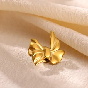 Élégante broche en forme de nœud en acier doré présentée de près sur un tissu beige