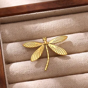 Macro détaillée d'une broche libellule en acier inoxydable doré sur une doublure en tissu
