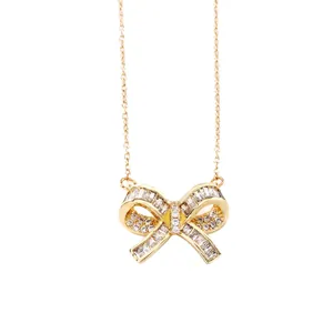 Elegant gold stainless steel bow necklace with sparkling crystals on white background