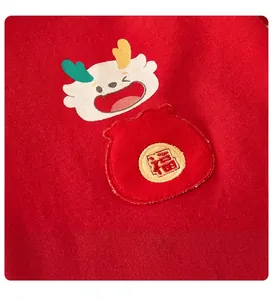 Gros plan d'une tenue de bébé en coton rouge avec broderie de dragon et caractère Fu