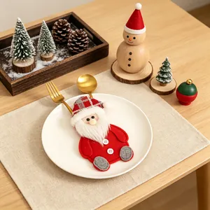 Detailopname van een feestelijke Kerstman bestekhouder op een wit bord met goud bestek.