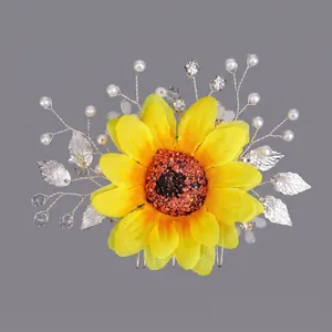 Peigne à cheveux tournesol jaune avec feuilles argentées, perles et strass sur fond gris.