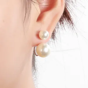 Close-up view of elegant double-sided pearl earrings featuring large and small beads on the ear