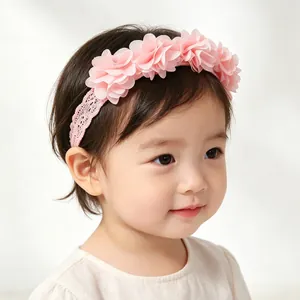 Adorable baby girl wearing a pink elastic headband decorated with soft chiffon flowers.