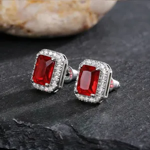 Detailed macro view of square silver stud earrings featuring a red stone and halo zircons