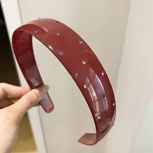 Close-up of a retro burgundy acrylic wide headband featuring sparkling multi-colored rhinestones