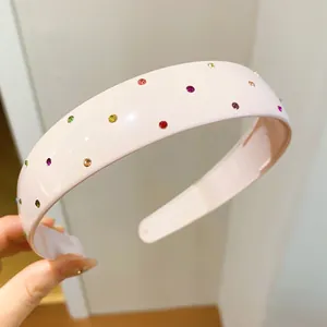Close-up view of a pink acrylic headband decorated with colorful rhinestones and smooth finish